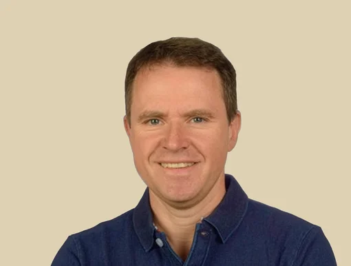 Professional headshot of Dr. Gregor M&ouml;ckel, smiling and wearing a navy blue polo shirt, set against a brown background.