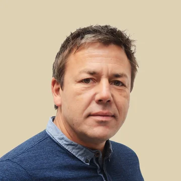 Headshot of Stephan Warnat, CEO, wearing a blue button-down shirt, set against a brown background.