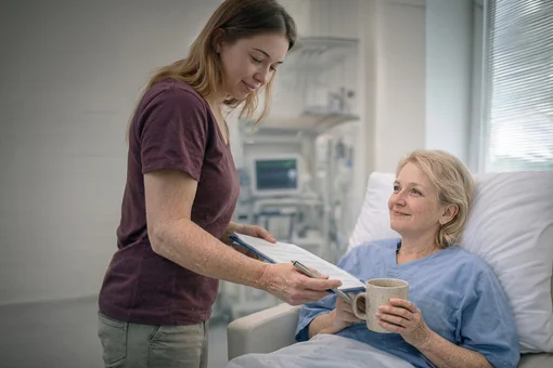 A female physical therapist in a white uniform guiding a male patient through arm mobility exercises in a bright, modern therapy clinic.