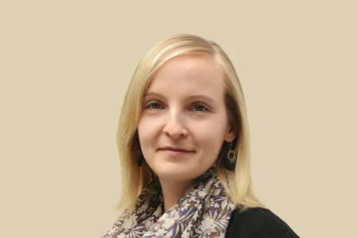 Corina Silber, Office Manager Professional headshot of Corina Silber, an office manager, wearing a patterned scarf and smiling against a brown background.