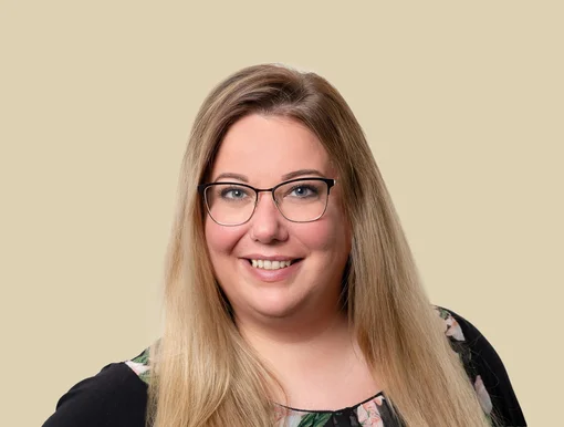 Professional headshot of Christiane Arends, an office manager, wearing glasses and smiling against a brown background.