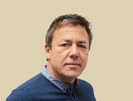 Headshot of Stephan Warnat, CEO, wearing a blue button-down shirt, set against a brown background.
